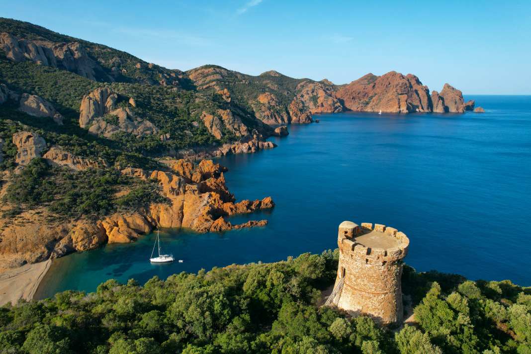 Anchorage amidst the rocky backdrop of Marina d'Elbo. High above the bay is an old Genoese tower that was once intended to protect the island from pirates