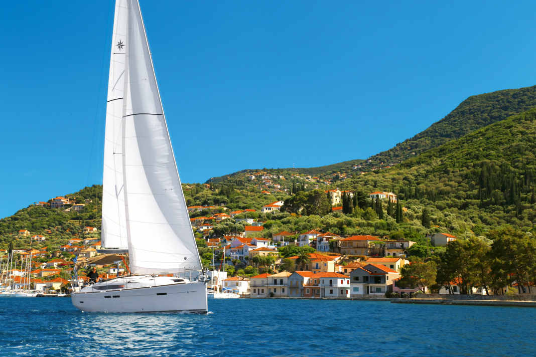 Eine Yacht segelt vor dem Ort Vathy auf der Insel Ithaka