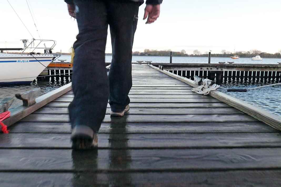 The protagonist walks across the footbridge, only his feet are visible
