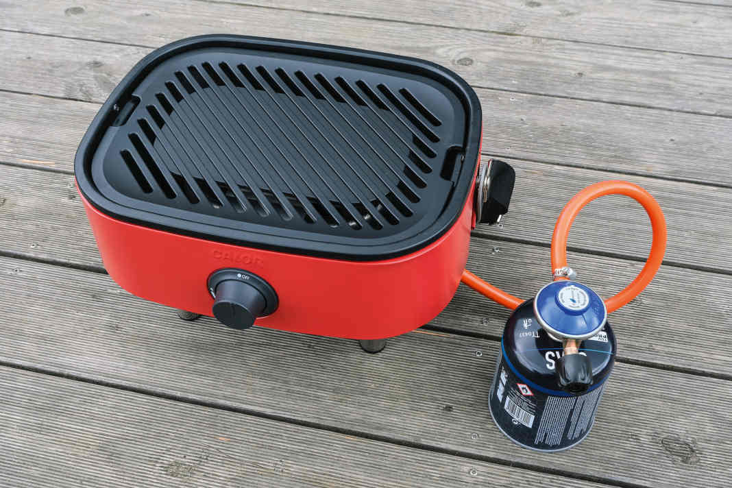 Tragbarer Grill mit praktischem Schneidebrettchen.