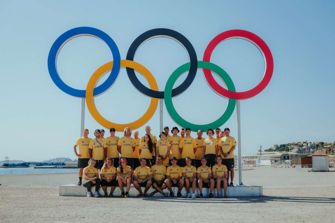 The national sailing team and their coaches at the five Olympic XL rings on the beach in Marseille