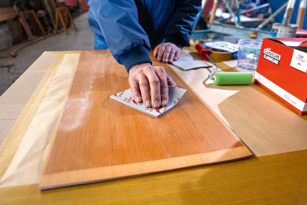 Anschleifen: Das Holz ist in gutem Zustand und mit einem harten Klarlack versiegelt. Damit der weiße Lack gut haftet, wird die Oberfläche mit Schleifvlies ange­raut, bis sie gleichmäßig matt ist