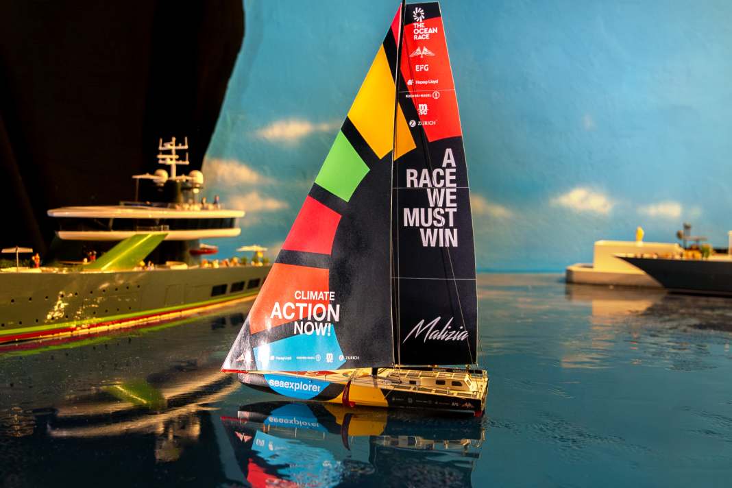 The Malizia Seaexplorer model sails in front of typical Monaco yachts.