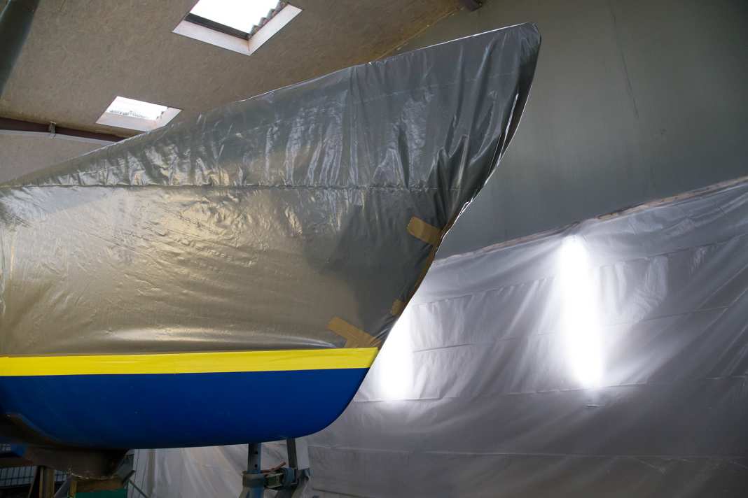 Vor dem Strahlen wird das Überwasserschiff staubdicht verpackt, am Wasserpass schützt robustes Klebeband das Gelcoat