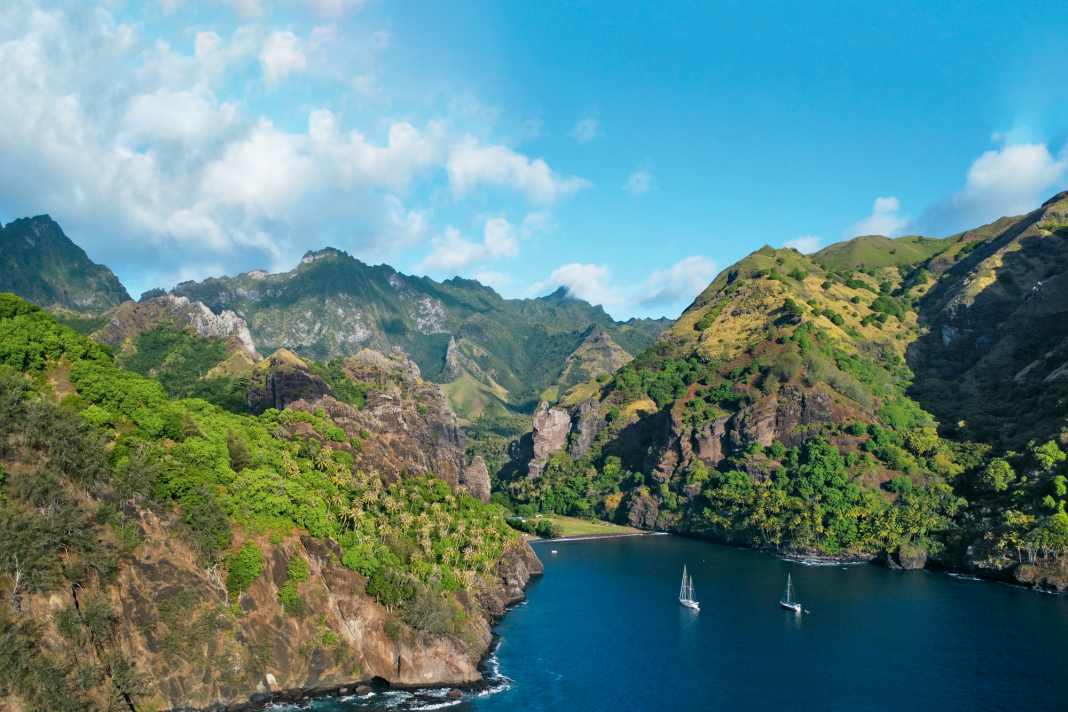 Two blue water sailors at anchor in the Bay of Virgins on the west coast of Fatu Hiva.  In the narrow valley between the rocks lies the village of Hanavave
