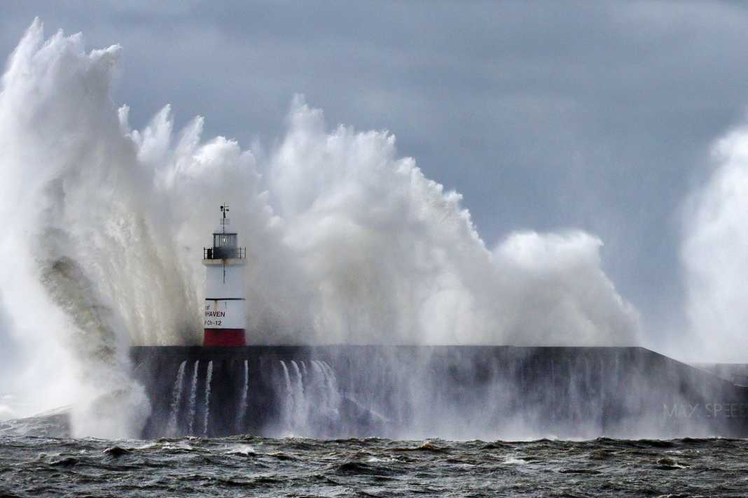 Wellen schlagen gegen die Hafenmauer des Leuchtturms von Newhaven in Newhaven, Großbritannien