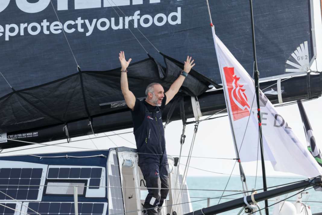 Fabrice Amedeo throws his arms up as he crosses the finish line.