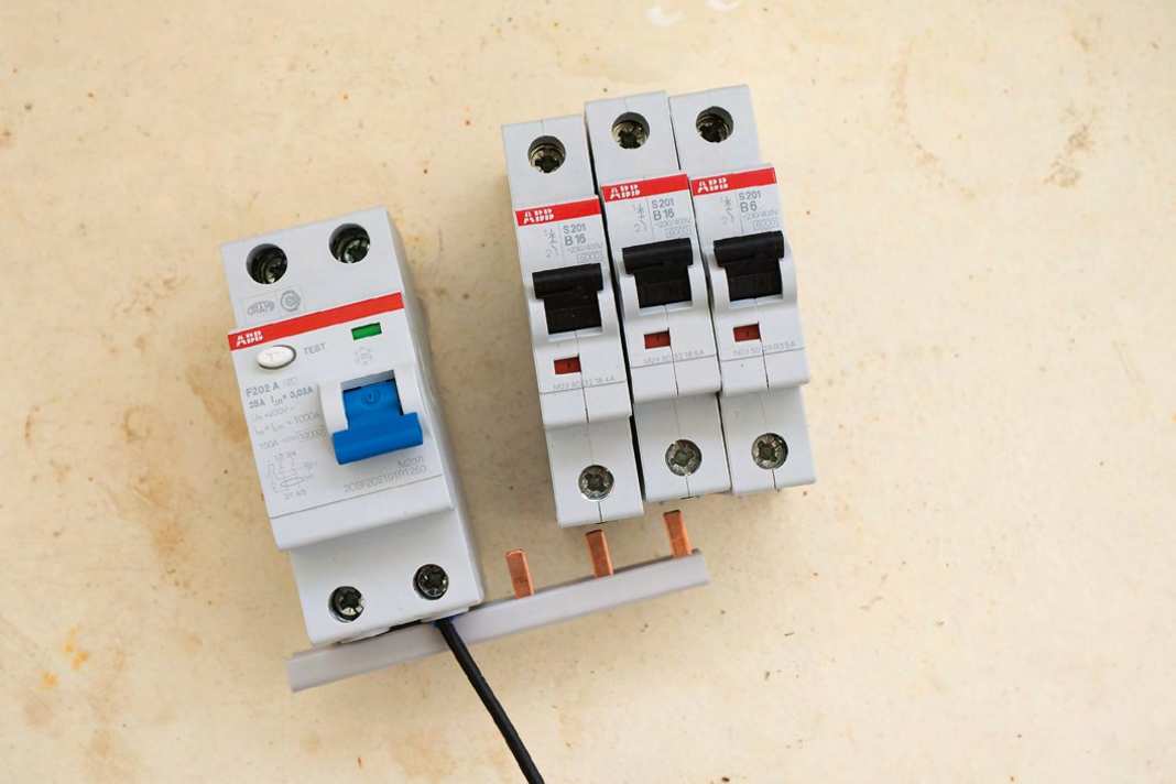 Fehlerstromschalter und Sicherungen werden durch eine Phasenschiene gekoppelt. Der Neutralleiter kommt auf eine Sammelschiene. Die Adern sind nummeriert, daher entfällt ...