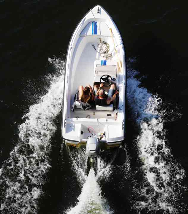 Sodertalje, Sweden - July 24, 2021: High angle view of an open tw seated small motorboat with two people on board travels at speed.