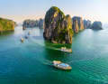Ausflugsboote in langer Prozession auf der Halong-Bucht im Norden Vietnams nahe der Grenze zu China. Monumentale Karstfelsen prägen die Landschaft
