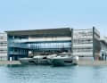 Head office: Offices are located behind a midnight blue façade and under a wing-shaped roof. Yachts are delivered or configured in the almost identical building opposite.  Even the bollards shine in Riva aquamarine