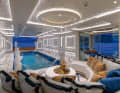 Beach club: water features and illuminated wall reliefs flank the pool. Behind the sliding glass door is the shisha lounge with a folding balcony
