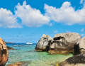 A charter catamaran in front of the striking rock formations of The Baths on Virgin Gorda. The spot is one of the most famous in the entire archipelago