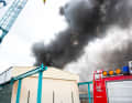 A large, dark column of smoke billowed out of a burning hall on the site of the Lürssen-Kröger shipyard