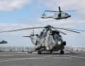 Sea King helicopter stands on the flight deck of the Dutch dock landing ship HNLMS Rotterdam and an NH-90 NTH Sea Lion (right) flies past during the military evacuation exercise Schneller Adler 2022 in the Kiel Fjord on 3 May 2022.