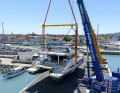 Two cranes lift the yacht.