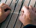The protruding sealing compound is cut flush to the height of the teak rods using a sharp cutter blade (wide version)