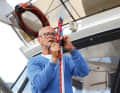 The eye of the line is placed over the tip of the boat hook and inserted into the Sailmatic clamp with the lower end of the eye
