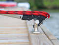 The spliced-in eye of the line is attached to a metal bracket. The hook is placed over the cleat and the mechanism is released by pulling on the boat hook