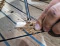To get the screws deeper into the wood, the holes are re-drilled. A template with a suitable hole guides the Forstner bit from the outside, as its centre point does not fit into the old hole