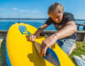 Vor dem Kleben wird die Position genau in der Flucht vom Bug zur Finne markiert, sonst erreichst du genau das Gegenteil von Geradeauslauf und das Board wird zum Kreismeister. Bei unserem ersten Testboard, einem Croslake Bellagio, das mit der tief im Wasser gleitenden Nase bereits serienmäßig sehr spurstabil läuft, konnten wir eine Verbesserung von etwa 15 Prozent ausmachen – bezogen auf die maximale Anzahl von Paddelschlägen auf einer Seite ohne allzu große Kursabweichungen. Bei den richtigen "Lämmerschwänzen", sehr nervösen, kurzen Boards mit runder Nase, dürfte sich das stärker bemerkbar machen. Eine gute Paddeltechnik kostet zwar weniger, bringt viel, gibt’s aber leider auch nicht von heute auf morgen gratis. Infos: www.croslake.com, 99 Euro