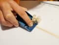 Beim Schleifen mit Schleifpapier bleibt der Stringer vorgewölbt. Um hier Schwachstellen im Laminat zu vermeiden und für eine schön glatte Fläche wird dieser mit einem Taschenhobel (Tipp: Minihobel mit Rasierklingen aus dem Baumarkt) vorsichtig abgehobelt. Zum Einstellen den Hobel auf eine Glasplatte stellen, unter die Vorderkante ein Blatt Papier legen, die Rasierklinge locker ausrichten, festziehen, fertig ist das Präzisionsinstrument.