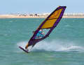 The start of the 360 variation is similar to a duck jibe. Immediately after the start, release the front hand from the boom and reach backwards crosswise to the end of the boom.