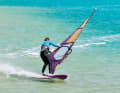 Using active foot control, you drop further over the leeward edge and start to let the luff tilt away with an outstretched front hand and guide the outhaul to windward so that it can turn through the wind.