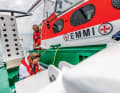 Surfer im Wasser werden immer mit dem kleinen Tochterboot des Seenotkreuzers gerettet. Dieses fährt huckepack auf dem Mutterschiff mit und wird bei Bedarf ausgeklinkt