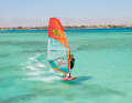 . Unhook yourself from the trapeze and place your back foot out of the loop onto the leeward edge.