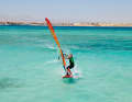As you switch to the other side just below the outhaul (rear corner of the sail), slide your back hand far back (wide grip)