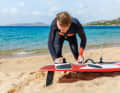 Lay the board with the tail facing the wind and, if possible, press the fin into the sand