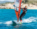 If a sudden gust hits your sail and threatens to pull you over the board to leeward, turn your upper body forwards and pull the mast towards your body with your front hand
