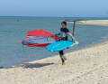 The carrying technique is a tip for small sails & foil boards - or for people with a large wingspan. To do this, turn the rig to the leeward side and flip the board upside down. Grip the windward edge of the board and the boom and lift the material. Always keep the rig on the leeward side when carrying it