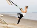 Pull the sling trainer with both arms and lean back slightly. The supporting leg is extended.