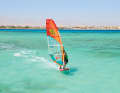 Unhook yourself from the trapeze and place your back foot out of the loop far onto the leeward edge.