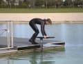 Man startet vom Steg aus gebückter Position. Brett und Foil befinden sich in Fahrtposition neben dem Steg. Die Hände halten das Board an den Rails fest. Die eine Hand stabilisiert das Board weiter vorne und die andere näher am Heck. So bleibt das Brett austariert, um es beim Anlaufen sauber neben dem Steg herführen zu können. Der Frontflügel sollte sich dabei nur wenige Zentimeter unter der Wasseroberfläche befinden.
