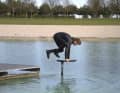 The jump is made over the front foot. Your body weight is well forward over the board. The foil now generates so much lift due to the approach speed that you can really support yourself on it. It is important to release yourself explosively from the dock at the moment of take-off and give one last strong impulse forwards. Your weight is now completely over the board. The arms are stretched and the legs come flying onto the board in a cat-like jumping motion.