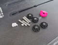 Das FoilFix Set besteht aus Stehbolzen, kleinen Spacern (weiß) zum Anpassen der Schraubenlänge, den Muttern (schwarz) und einem kleinen Werkzeug (pink)
