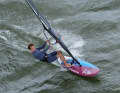 At full planing speed on a half-wind course, first take your back foot out of the loop and grip the boom as far forward as possible with your front hand.