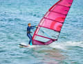 Change sides with hands and feet synchronised. Pull the back foot forwards towards the mast (heel to heel) and at the same time reach across to the new boom side with the old sailing hand (boom-to-boom).