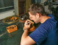 Engraver Daniel Janssen, bent over his workpiece, which is placed on a round plate. In this way, the copper plate to be worked on can be quickly turned in all directions