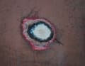Après le ponçage jusqu'au gelcoat, on voit ici une rupture du gelcoat avec une bulle d'osmose.