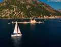 Charter yacht in front of Gospa od Skrpjela, in German: Maria vom Felsen. The harbour town of Perast in the background