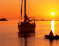 Una serata idilliaca all'ancora. Il sole al tramonto bagna il mare di calde tonalità rosse. Di notte, le luci dei fari scintillano sul mare.