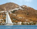 Eine Yacht segelt in der Bucht Livadi am Fuß der Altstadt von Serifos. Die thront hoch oben am Berg und ist unbedingt einen Besuch wert
