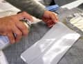 After removing the film, the adhesive surface of the patch is sprayed with additional adhesive. 3M 77 spray adhesive was used here. Either aim well or place a cover sheet of the nautical chart or similar underneath so that the whole sail does not become sticky
