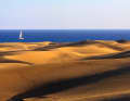 A sailing yacht rounds the southern tip of Gran Canaria, the striking dunes of Maspalomas. The Sahara is close.