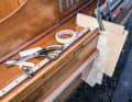 Measurement: The exact shape of the hull, rubbing strake, deck and genoa rail is measured using an improvised template made from scraps of wood, cardboard and adhesive tape.