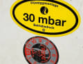 Der gelbe Aufkleber im Deckel des Gaskastens zeigt den Betriebsdruck der Anlage an. Darunter ist das Prüfsiegel mit dem  Datum der nächsten Wartung aufgeklebt.